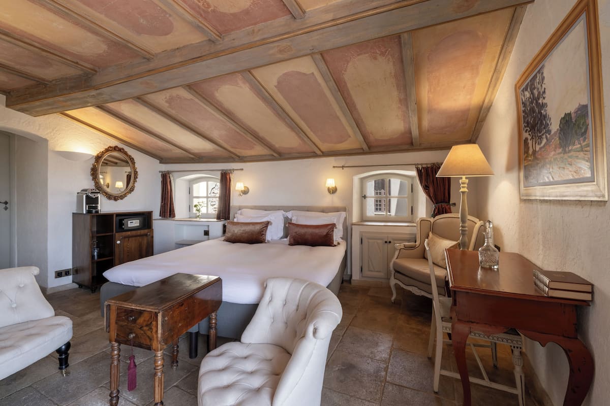A spacious bedroom with a large bed, a wooden desk, a chair, and a wardrobe.