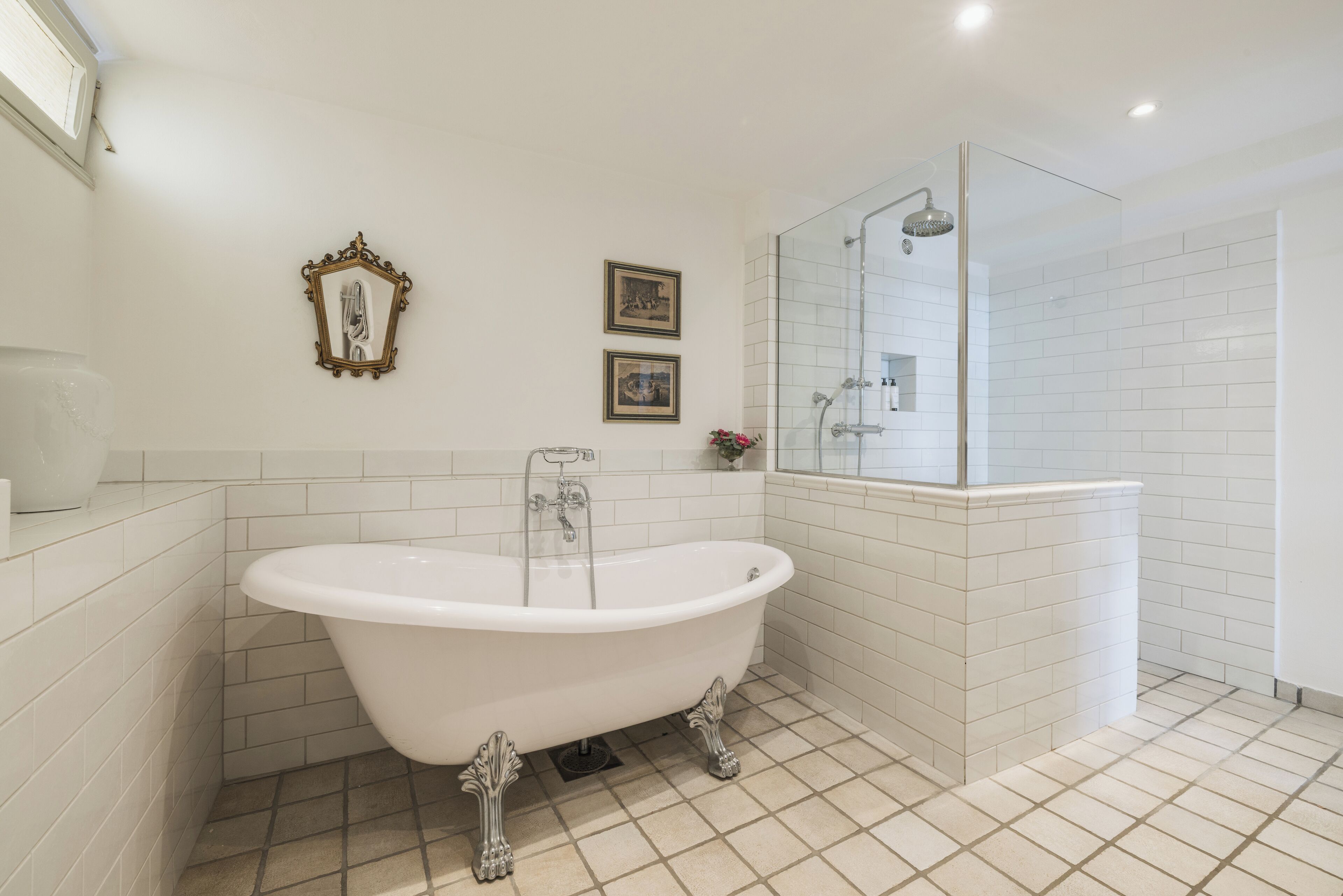 A bathroom with a freestanding bathtub, a glass-enclosed shower, and white tiled walls.