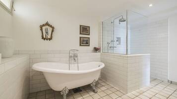 A bathroom with a freestanding bathtub, a glass-enclosed shower, and white tiled walls.
