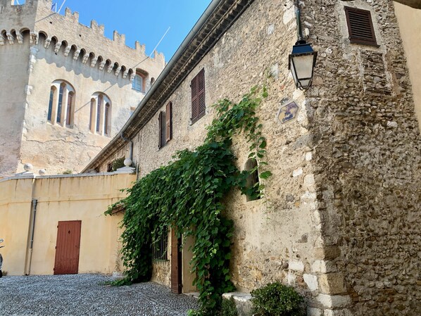 Un edificio storico con mura in pietra, finestre ad arco e un cortile acciottolato.