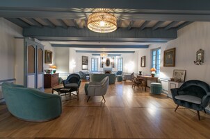 Amplia sala de estar con piso de madera, un gran candelabro y chimenea. Varias zonas de estar con muebles modernos.
