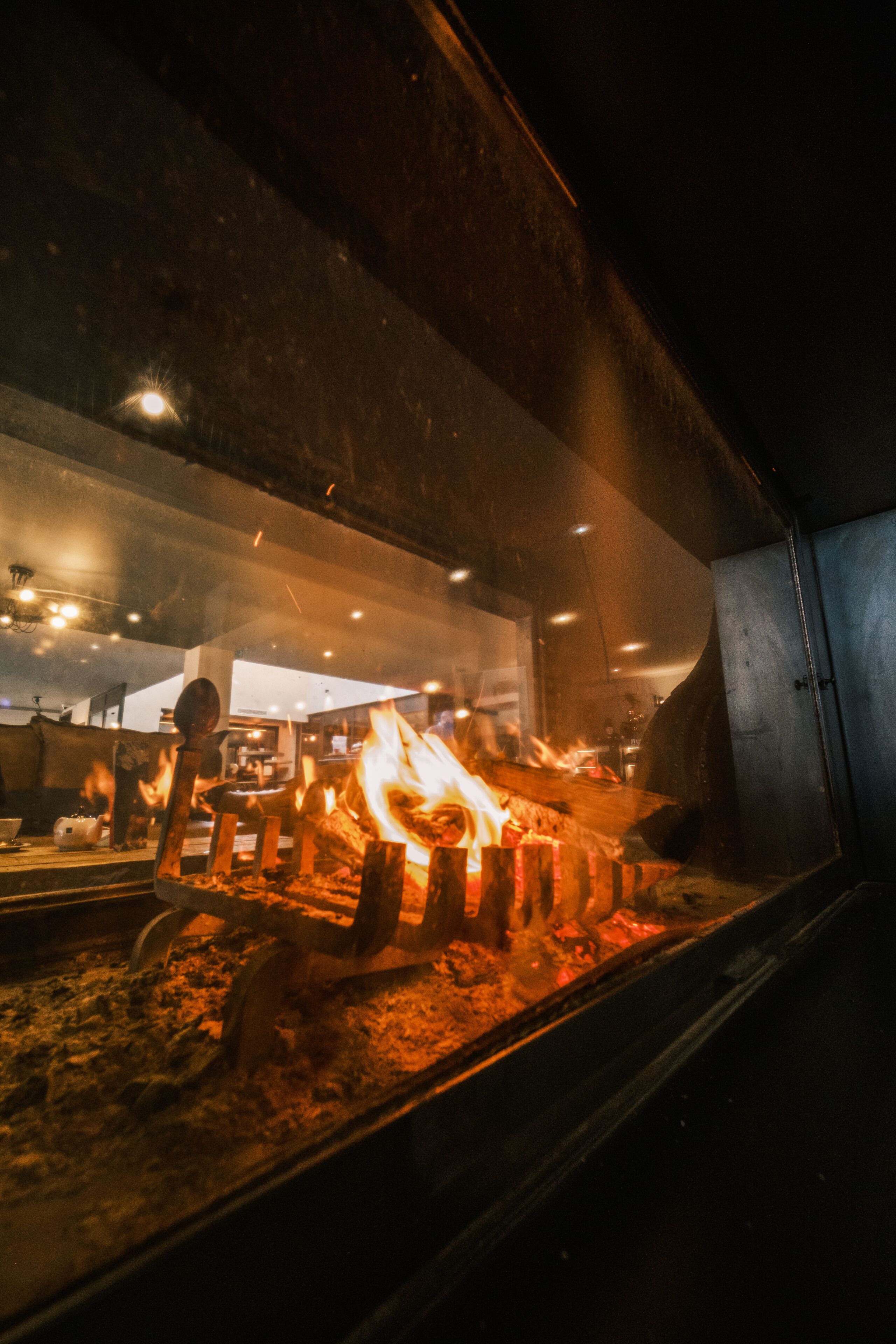 Horno de leña con llamas visibles y leños en su interior, indicando una zona para cocinar o asar.