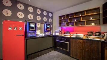 Una cocina moderna con un refrigerador rojo, una cafetera y estantes de madera con frascos.