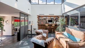 Un interior moderno con un sofá de cuero, una mesa de comedor de madera y una zona de bar con taburetes.