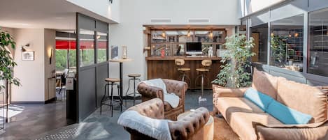 A modern interior with a leather sofa, a wooden dining table, and a bar area with stools.