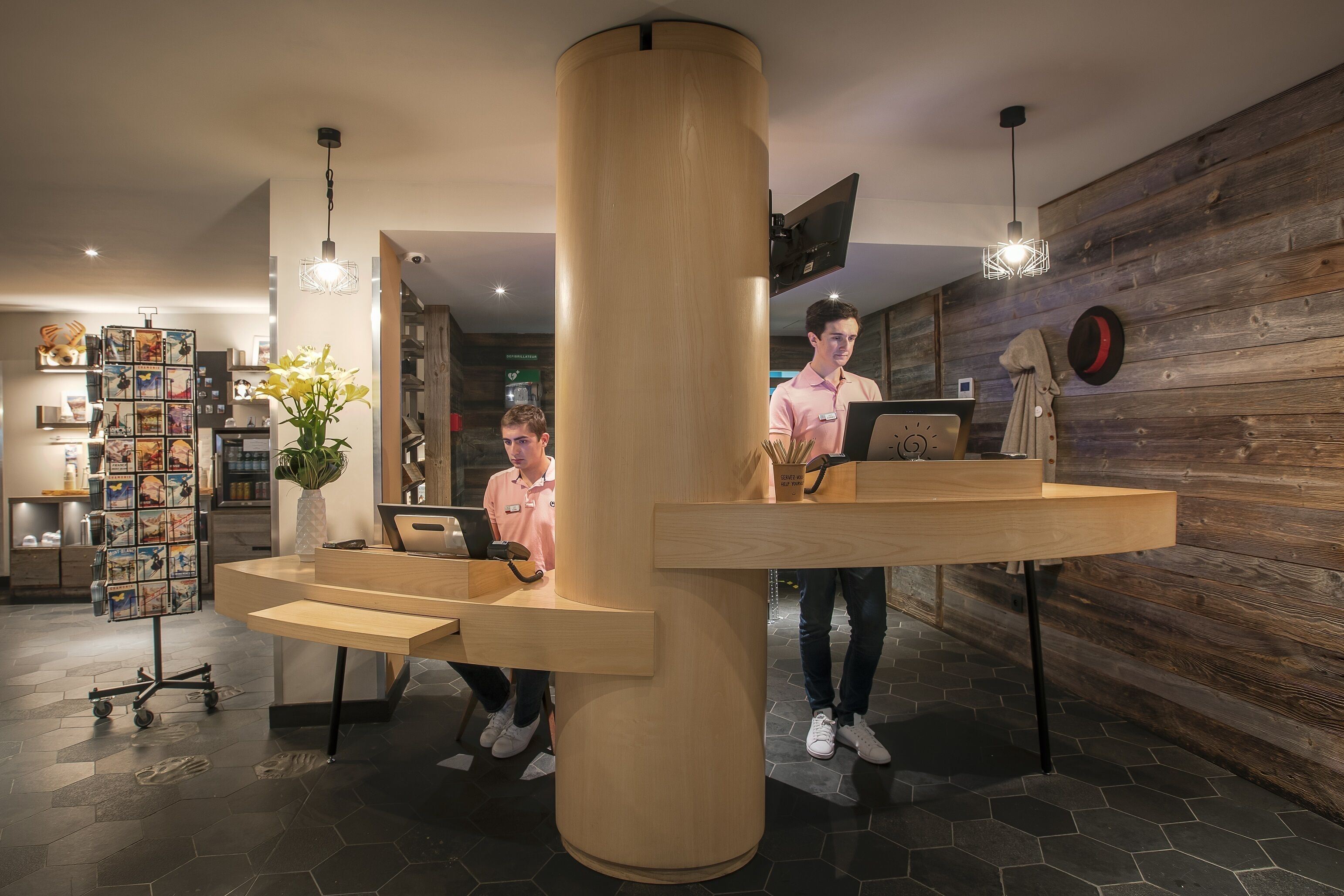 A reception desk with a wooden design, a modern light fixture, and a wall-mounted TV.