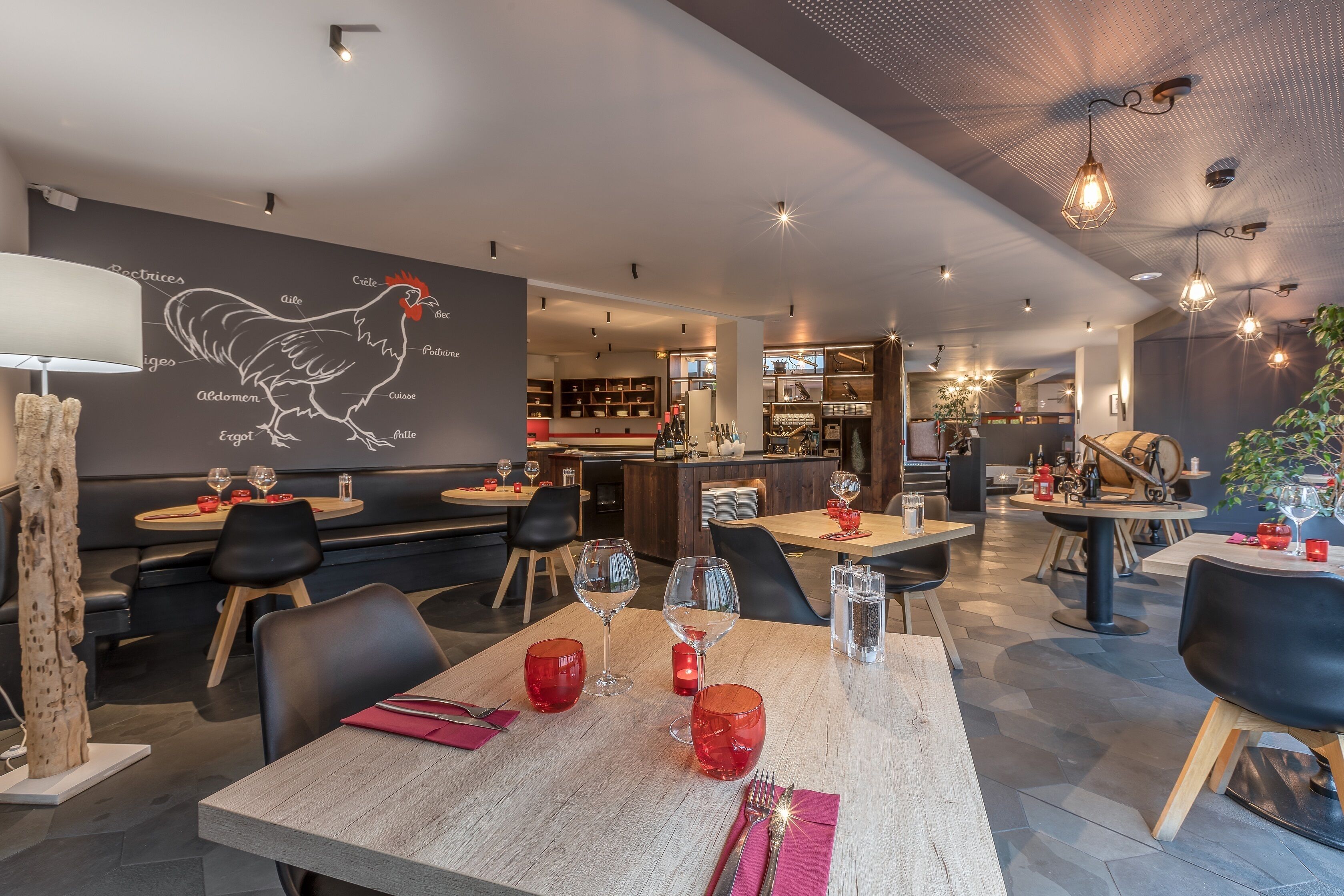A restaurant with wooden tables, black chairs, and red wine glasses.