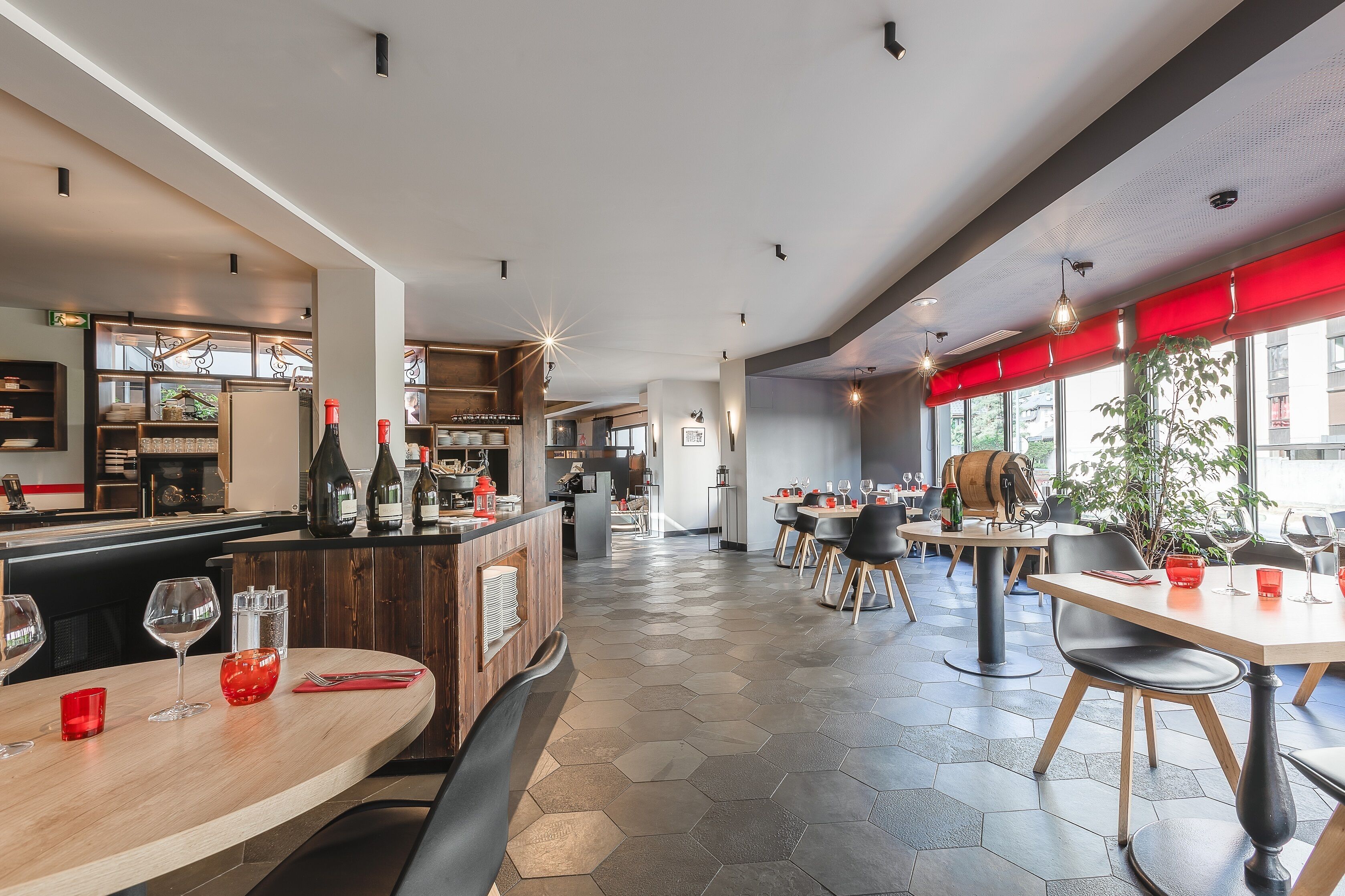 A modern restaurant interior with hexagonal flooring, wooden tables, and black chairs.