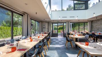 Un espace de restauration moderne doté de grandes fenêtres, de tables en bois et de chaises noires.