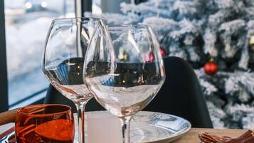 A dining table with wine glasses, a candle, and a Christmas tree in the background.
