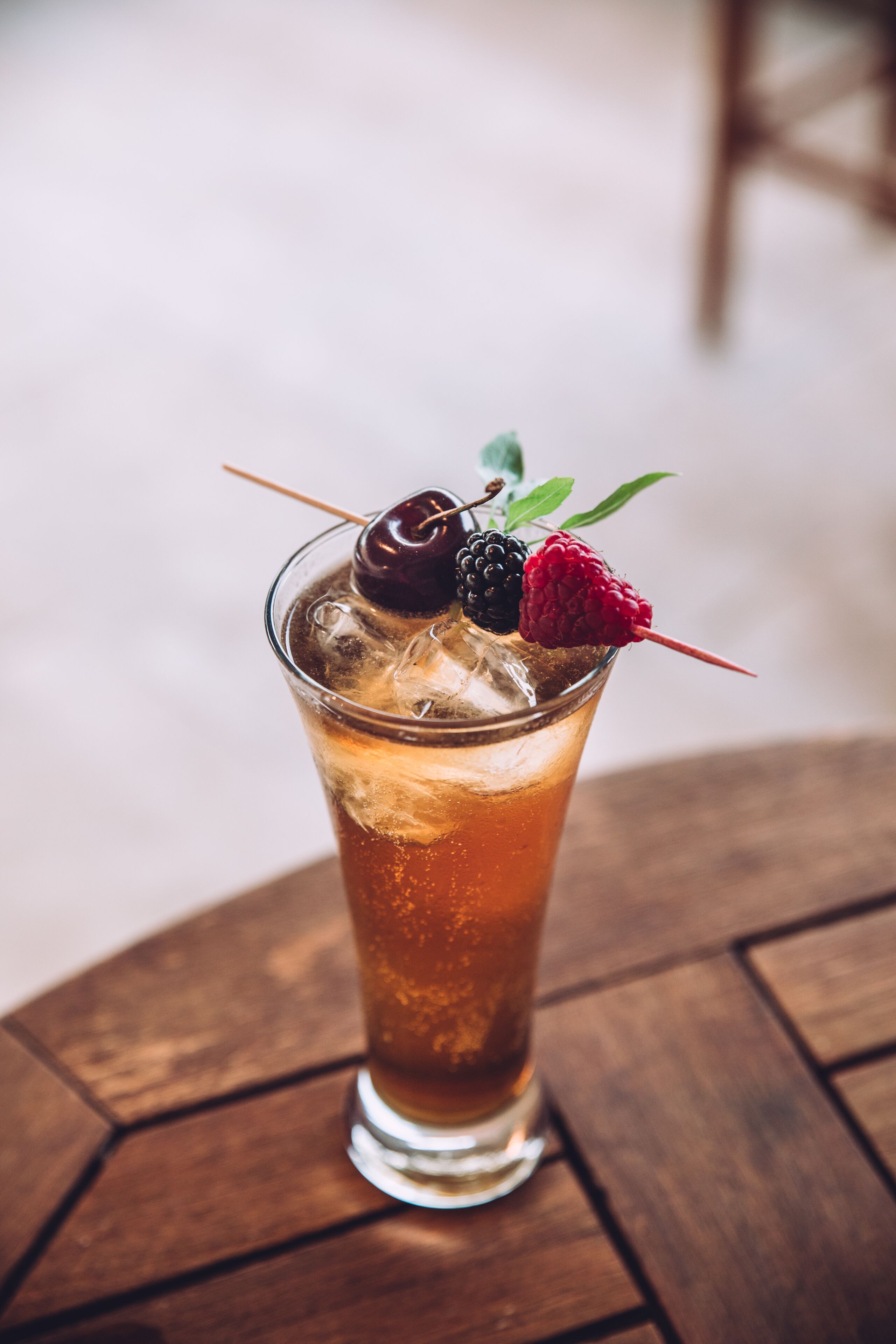 Un vaso de té helado con adorno de frutas sobre una mesa de madera.