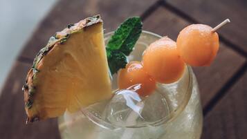 Un verre contenant une tranche d’ananas et des billes d’orange, posé sur une surface en bois.