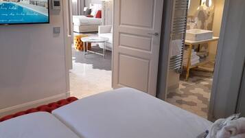 Une chambre d’hôtel avec deux lits, un téléviseur fixé au mur et une salle de bain visible à travers une porte ouverte.