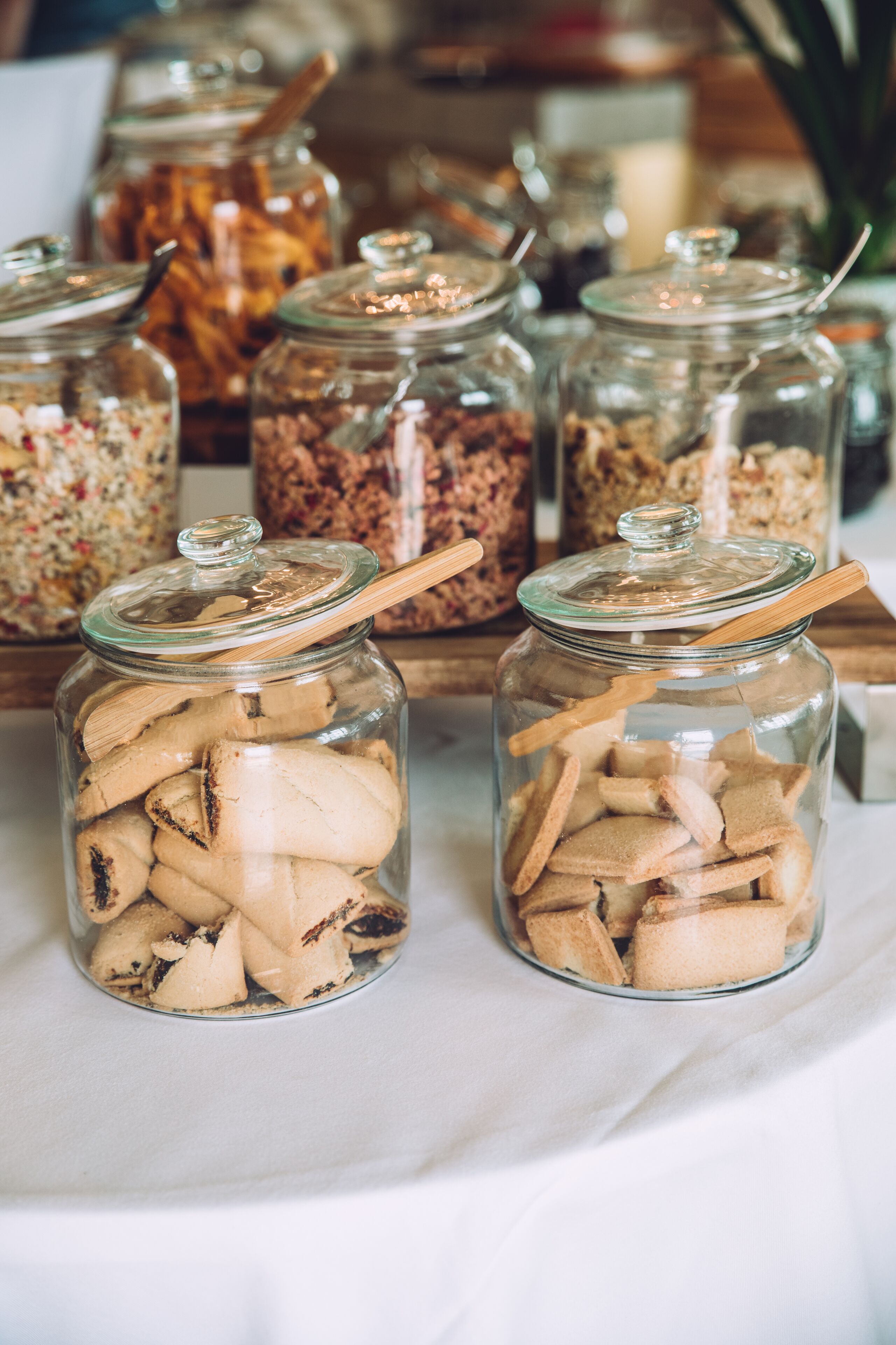 Des bocaux en verre avec des couvercles en bois contenant divers aliments.