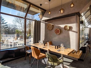 A modern dining area with a large table, chairs, and hanging pendant lights. - Novotel Le Mans (Le Mans)