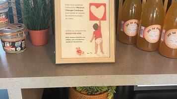 A framed sign with a child holding a heart, a jar of jelly, and bottles of juice on a counter.