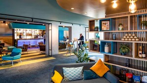 A modern lounge area with a bar, seating, and a bookshelf.
