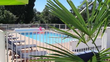Une piscine agrémentée d’un flotteur en forme de flamant rose, entourée de mobilier blanc disposé au bord de la piscine et d’une terrasse en bois.