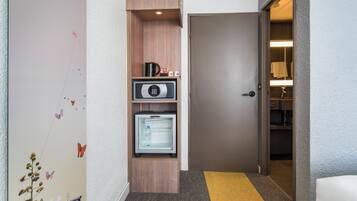 A hallway with a microwave, refrigerator, and a door leading to a bathroom.