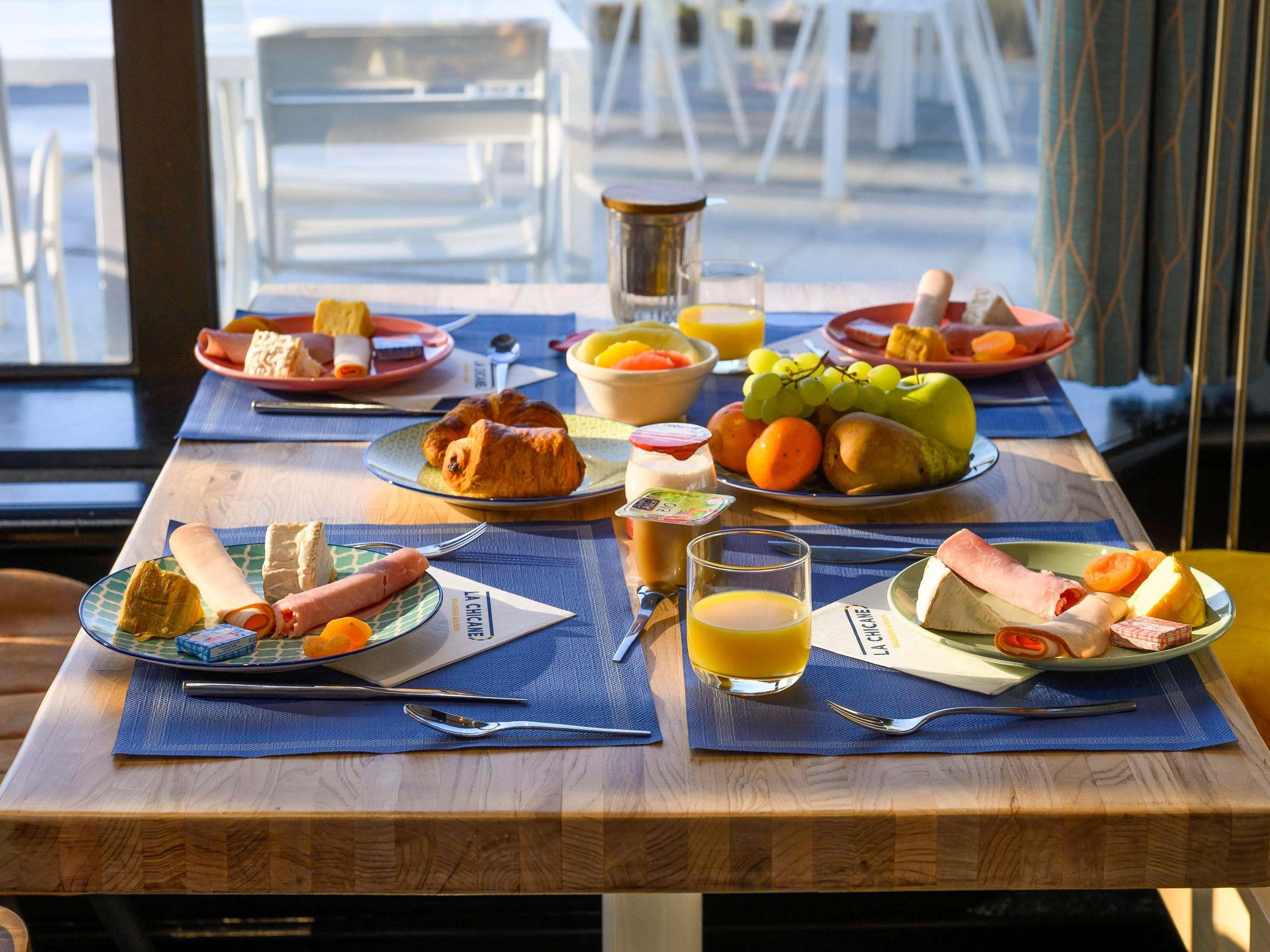 A breakfast table with plates of food, a glass of orange juice, and a bottle of water.