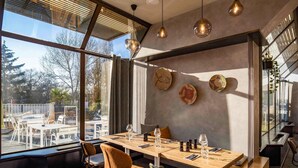 A modern dining area with a large table, chairs, and hanging pendant lights.
