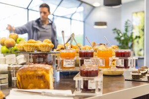 A breakfast buffet with pastries, jams, and apples.