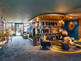 A modern interior with a curved seating area, a bookshelf, and a large teddy bear.