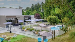 A modern outdoor patio with seating, umbrellas, and a pool.
