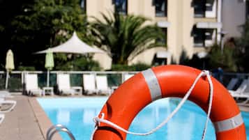 Una piscina al aire libre, sombrillas, sillones reclinables de piscina