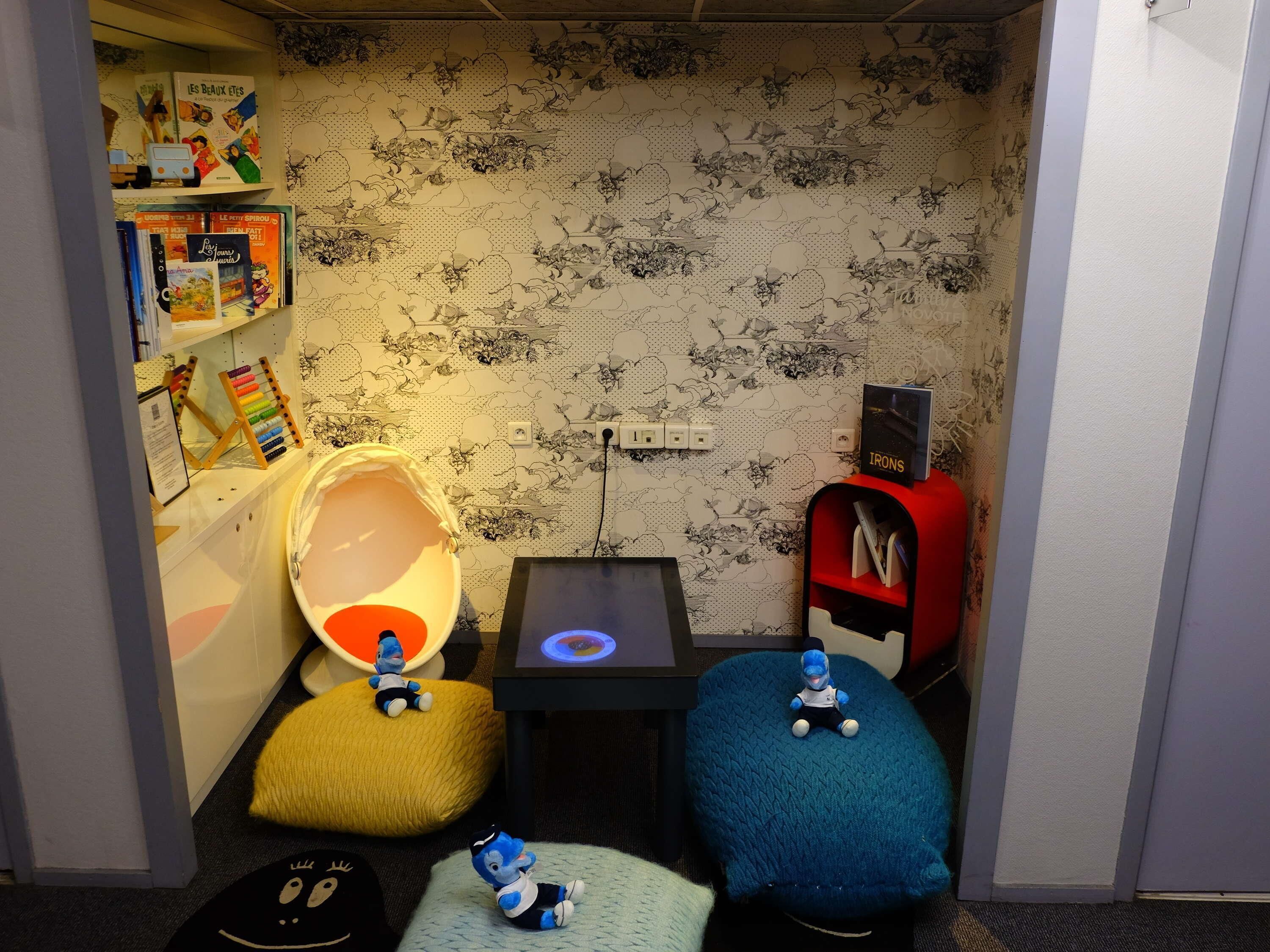 A cozy reading nook with a bookshelf, a lamp, and plush seating.