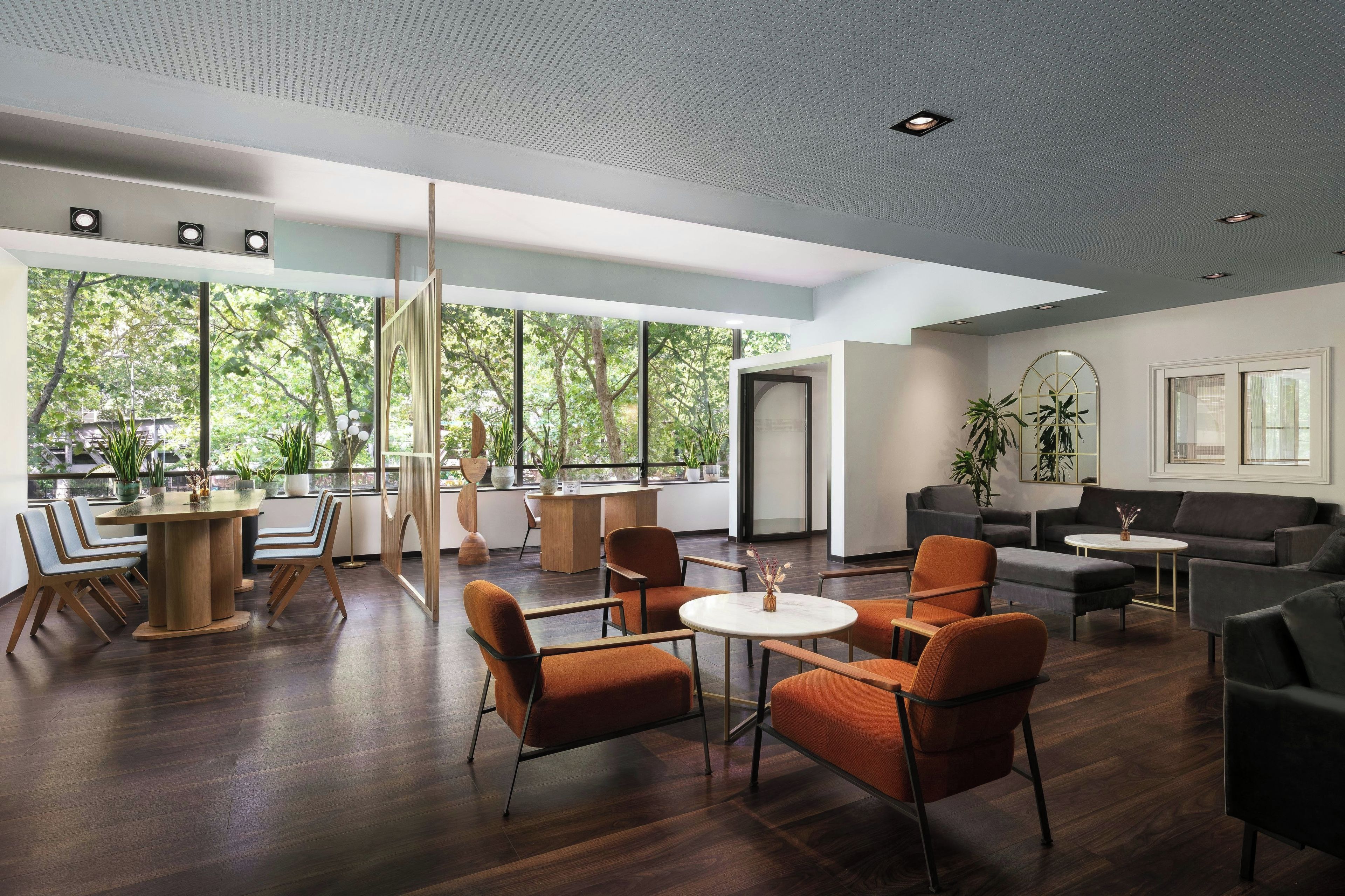 A modern interior with a dining area, seating, and large windows.