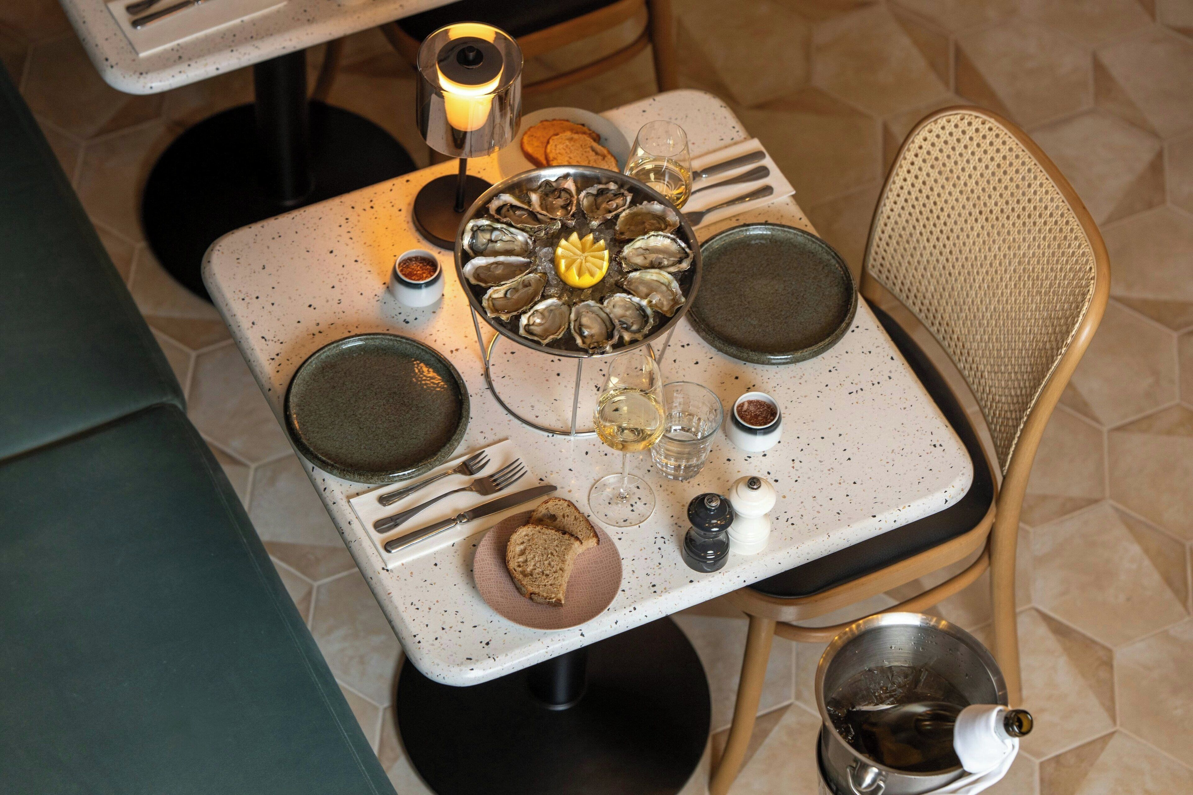 A dining table set with plates, glasses, and a bread roll.