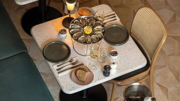 A dining table set with plates, glasses, and a bread roll.
