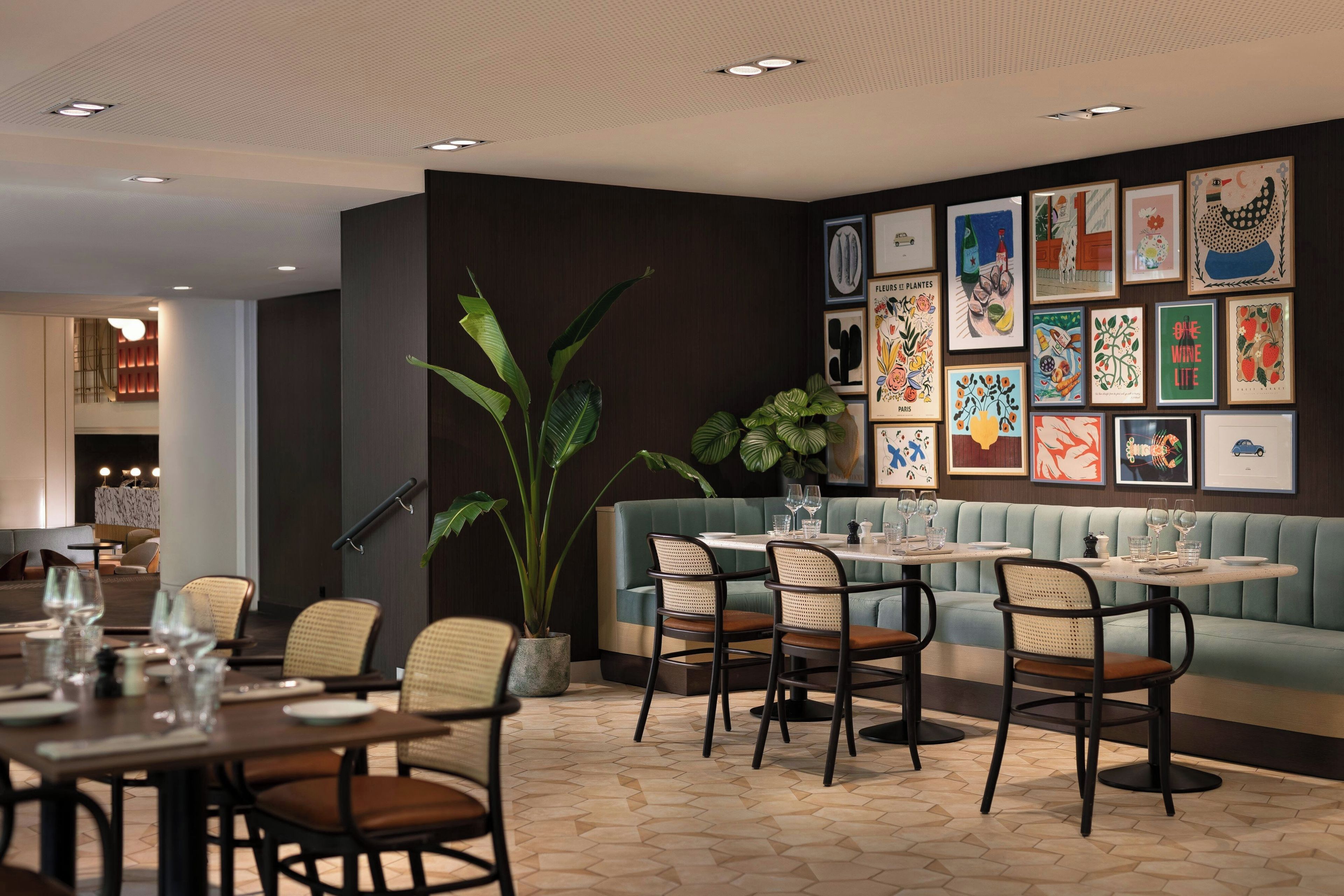 A restaurant interior with a dining area, seating, and a wall decorated with framed artwork.