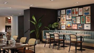 A restaurant interior with a dining area, seating, and a wall decorated with framed artwork.