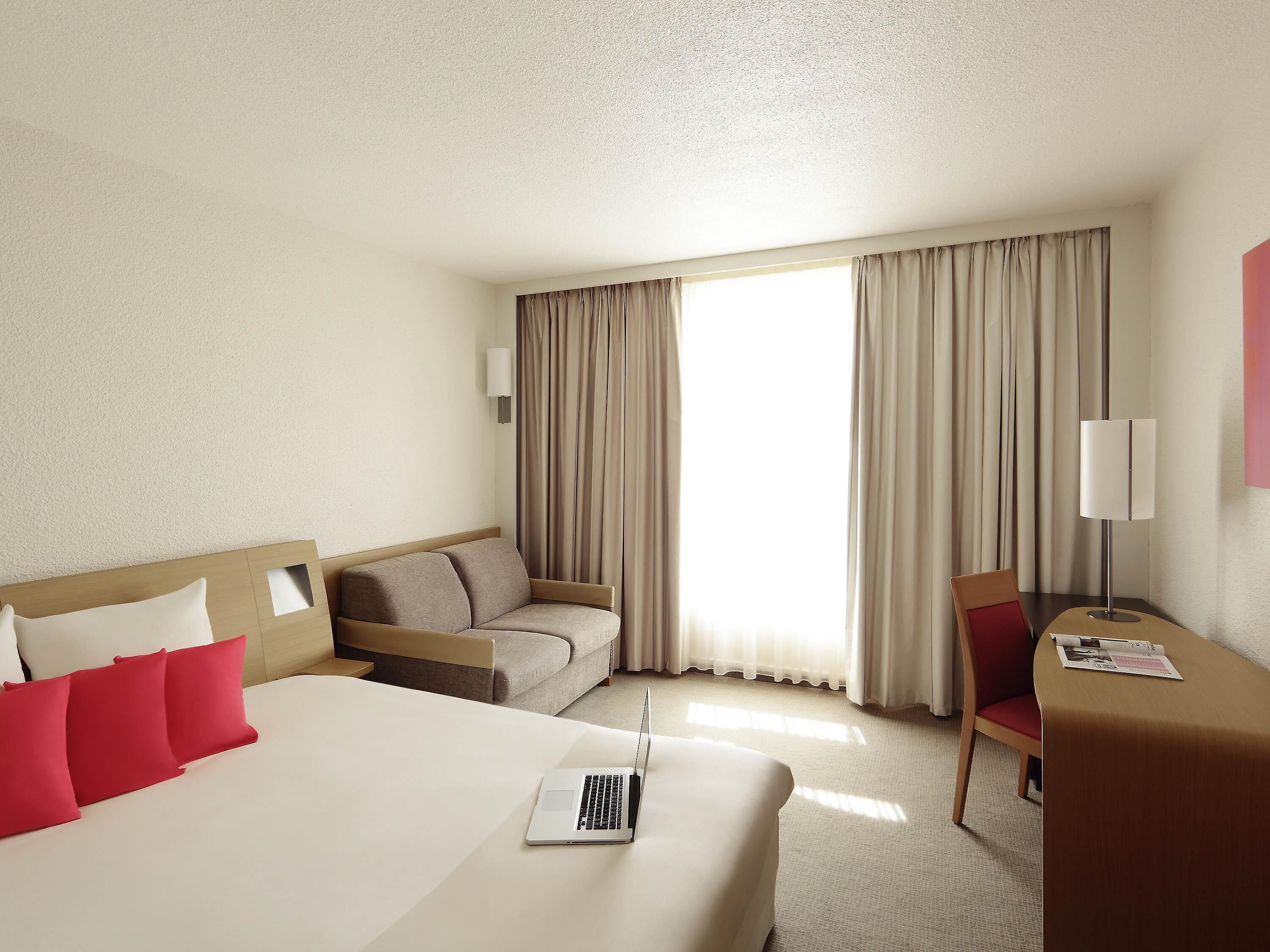 A hotel room with a bed, a sofa, a desk, and a chair.