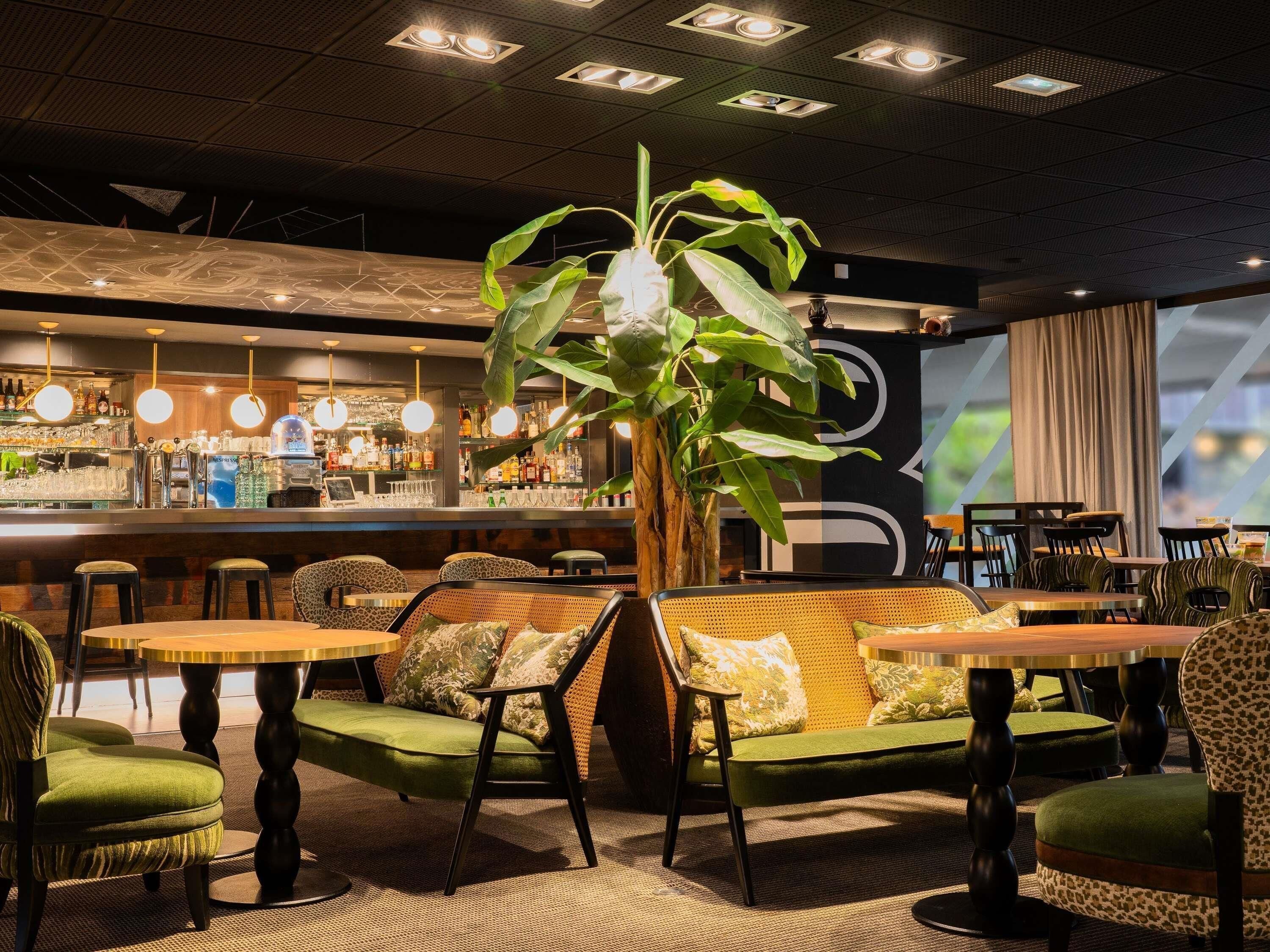 A bar area with a counter, stools, and hanging lights.