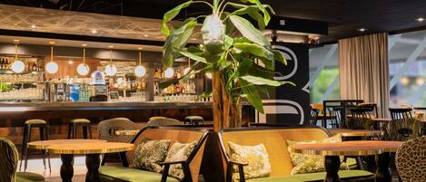 A bar area with a counter, stools, and hanging lights.