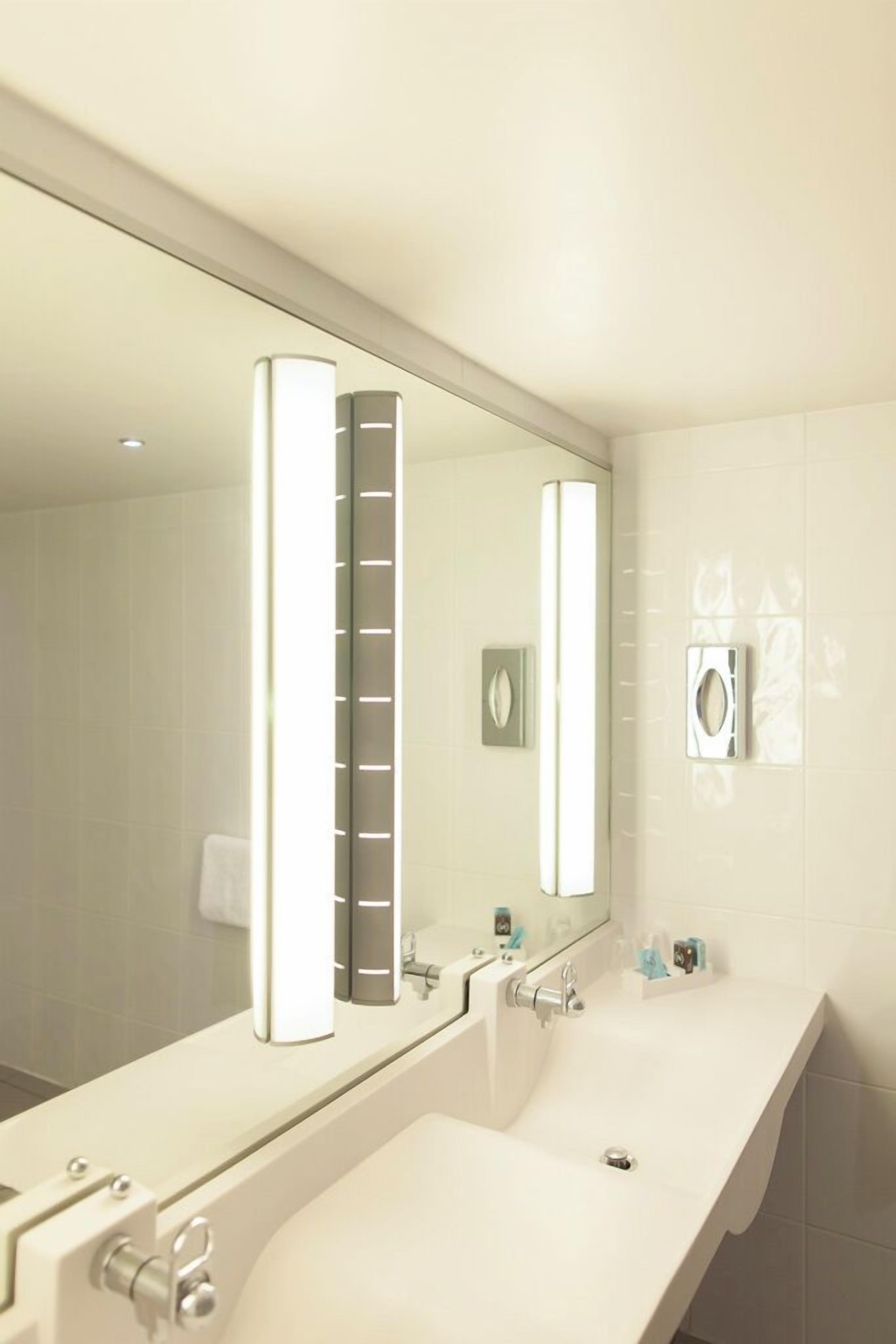 Een moderne badkamer met een grote spiegel, twee wasbakken en een handdoekrek.