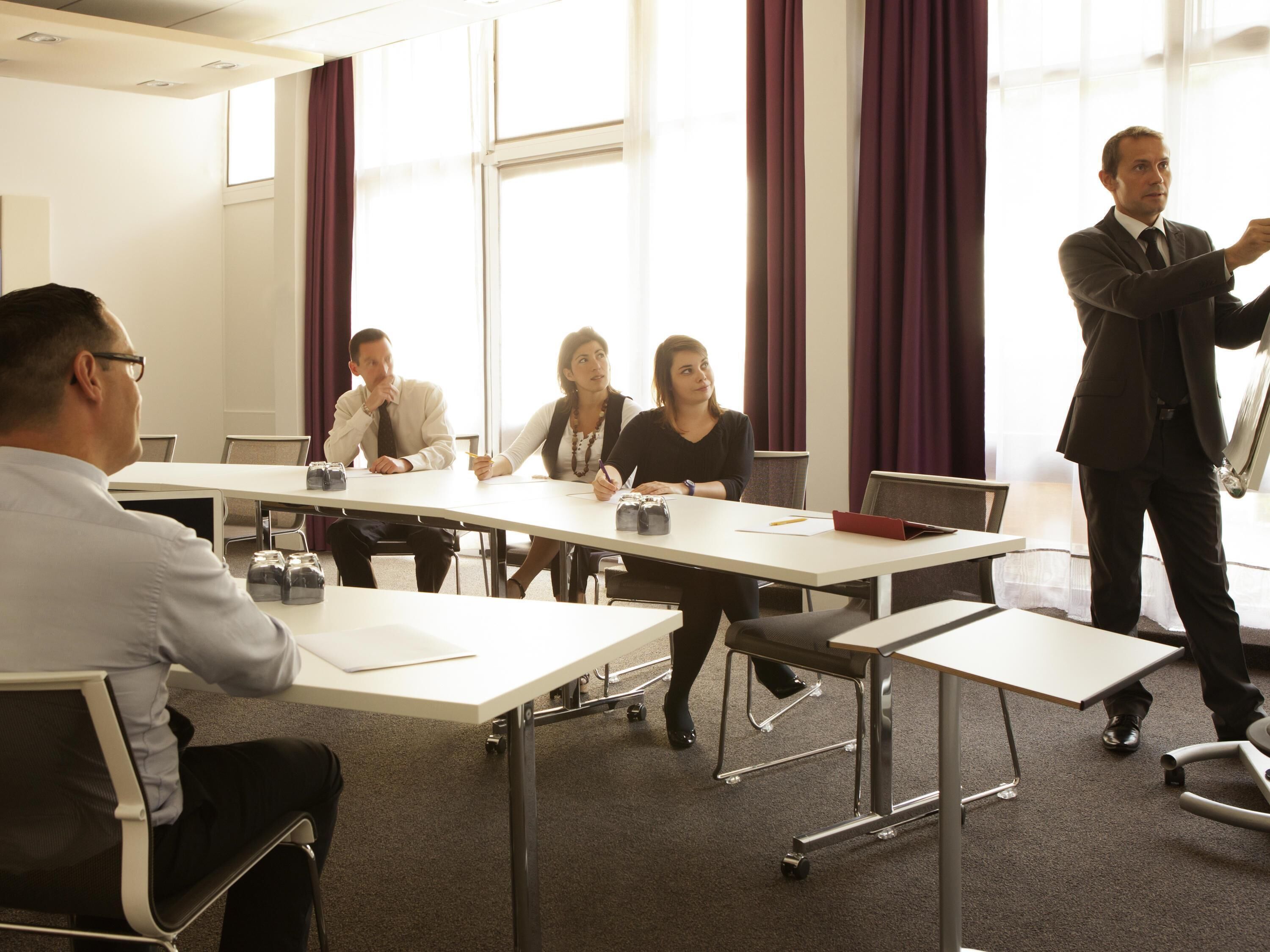 A conference room with a white table, chairs, and a presentation board.