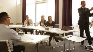 A conference room with a white table, chairs, and a presentation board.