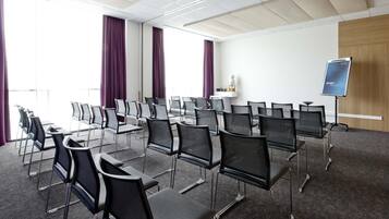 A conference room with rows of chairs, a projector screen, and a whiteboard.