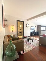 Een woonkamer met een bank, een salontafel, een vloerkleed en een grote spiegel.