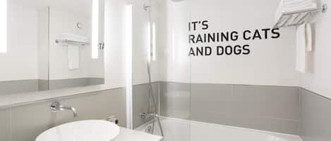 Un baño moderno con ducha de vidrio, lavamanos blanco y perchero para toallas.