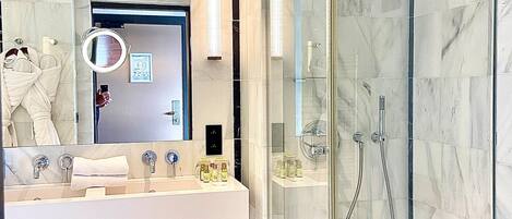 A modern bathroom with a glass-enclosed shower, a vanity with a mirror, and a toilet.