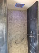 A modern shower area with a tiled wall, a handheld showerhead, and a wall-mounted faucet.