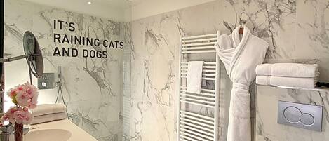 A modern bathroom with a marble wall, a white sink, a towel rack, and a toilet.
