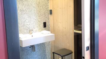 Une salle de bain moderne avec un lavabo blanc, des murs carrelés et un mur recouvert de panneaux en bois.