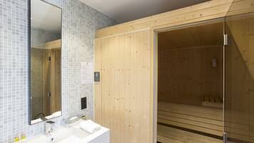 Un baño moderno con cabina de ducha de madera, un espejo grande y un lavabo blanco con artículos de aseo.