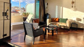 A modern living room with a large sliding glass door leading to a balcony, a sofa set, a coffee table, and a view of the cityscape. - Hôtel Cannes Centre Univers (Cannes)